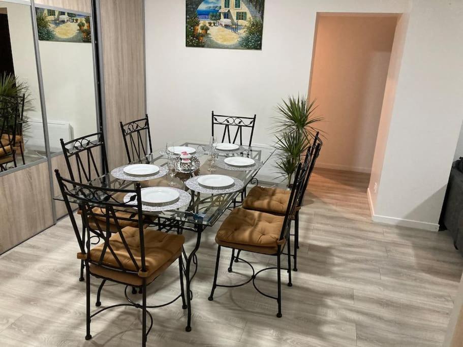 stół jadalny z krzesłami i szklany stół z talerzami w obiekcie Belle maison2 chambres pres du Paris 80m2 w mieście Villecresnes