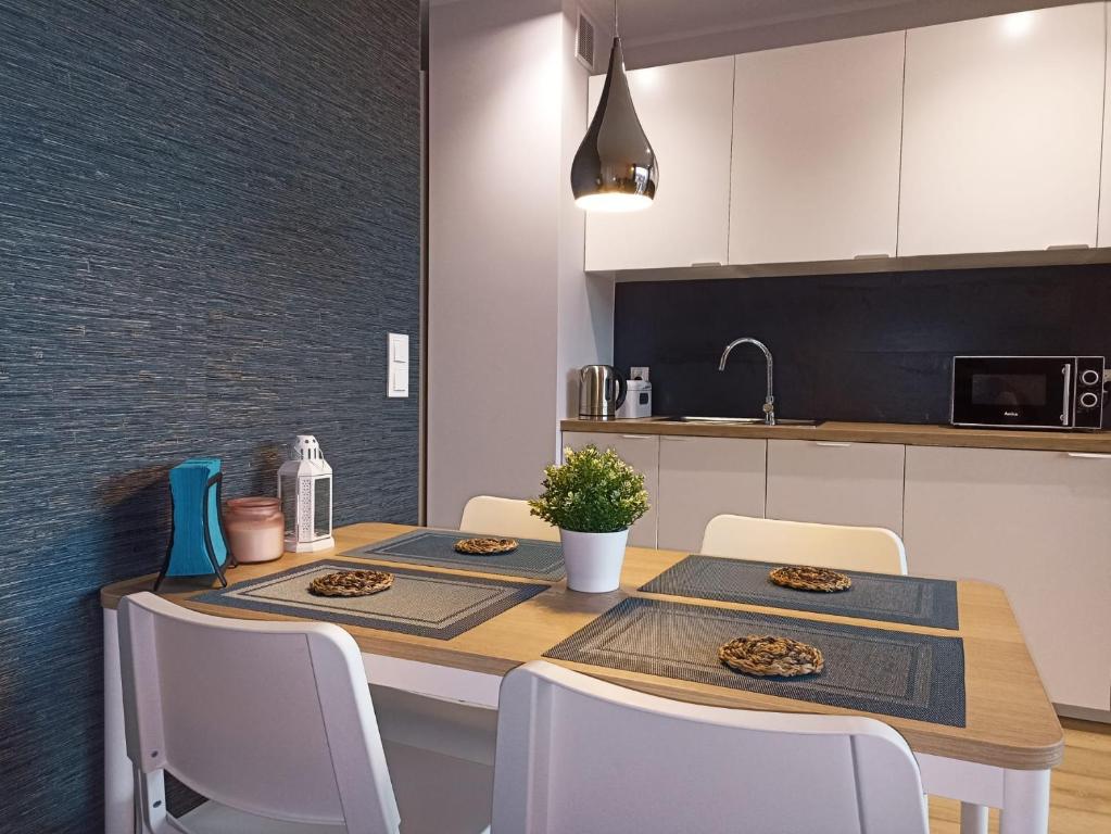 a kitchen with a dining table with white chairs at Apartament Alicja in Międzywodzie