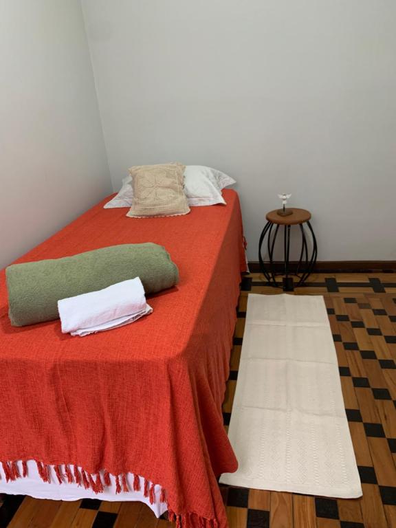 a bed with a red blanket and pillows on it at Quarto COMPÔ 6 in São João del Rei
