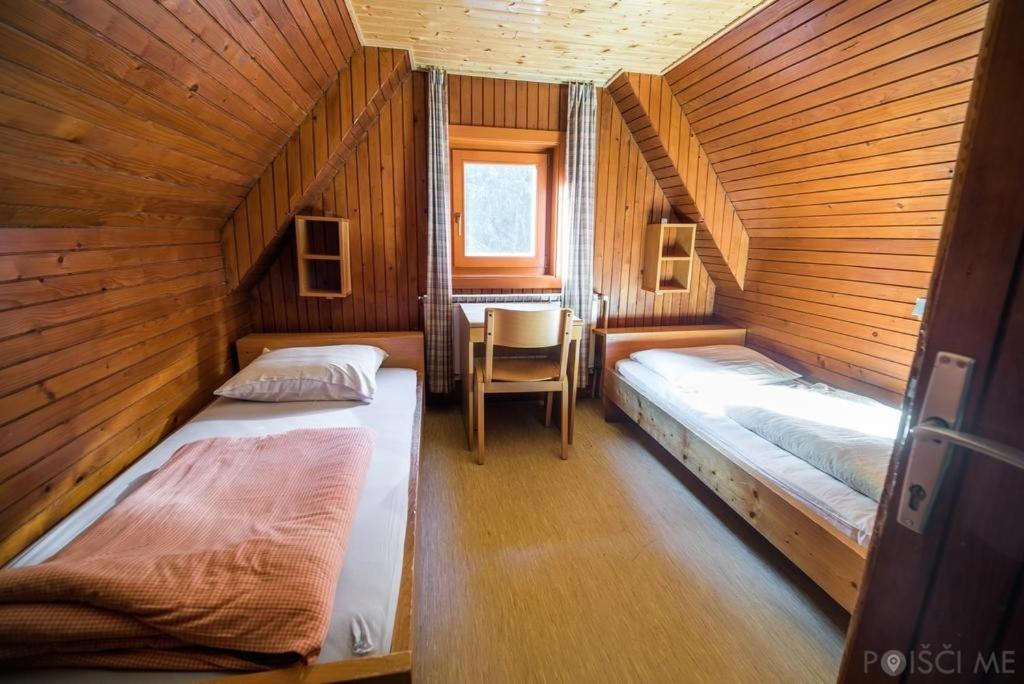 a room with two beds in a wooden cabin at Ruška koča in Hočko Pohorje