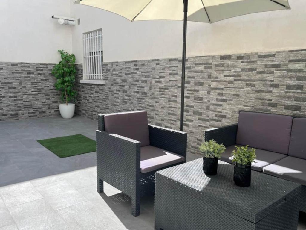 um pátio com 2 cadeiras, uma mesa e um guarda-sol em Luminoso apartamento con precioso y amplio patio em Carabanchel Alto