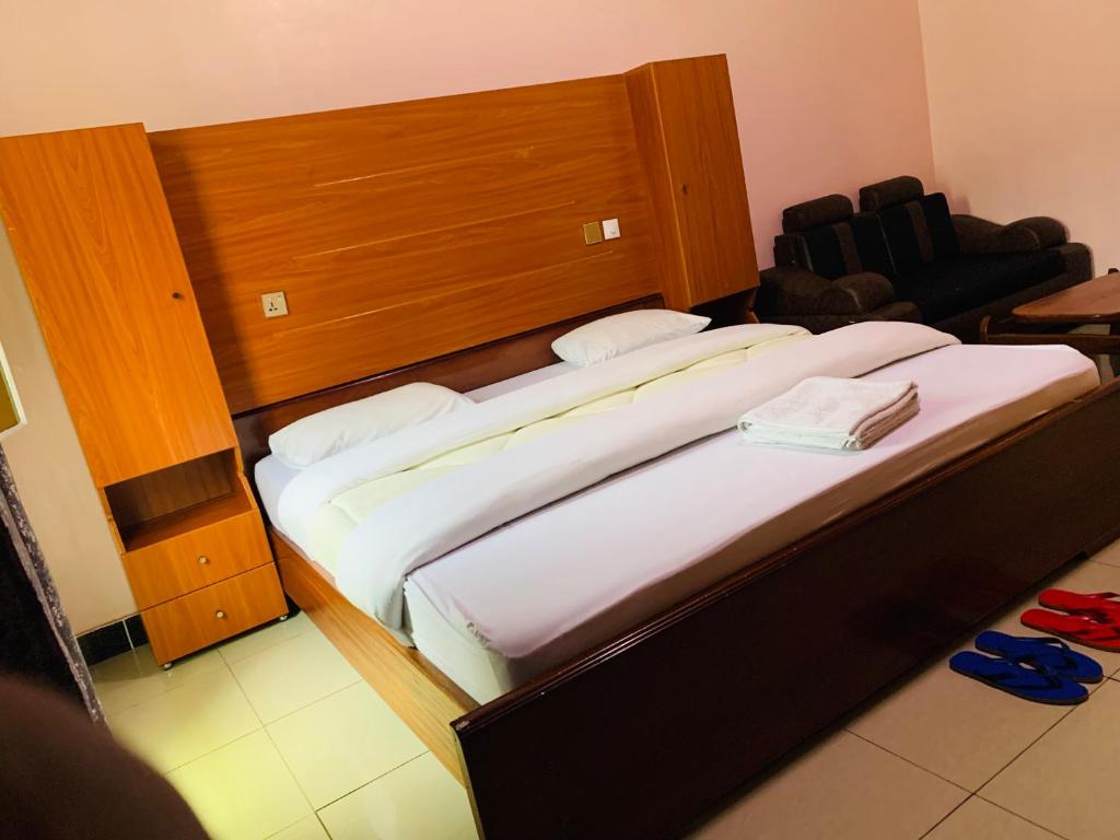 een slaapkamer met een groot bed met een houten hoofdeinde bij Arundinaria guest house in Gisenyi