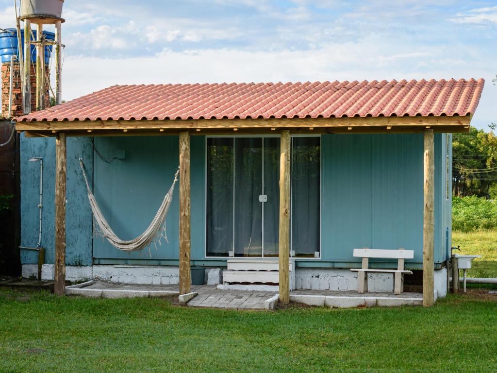 una casa blu con una panchina nell'erba di Kitbox PDR a Garopaba