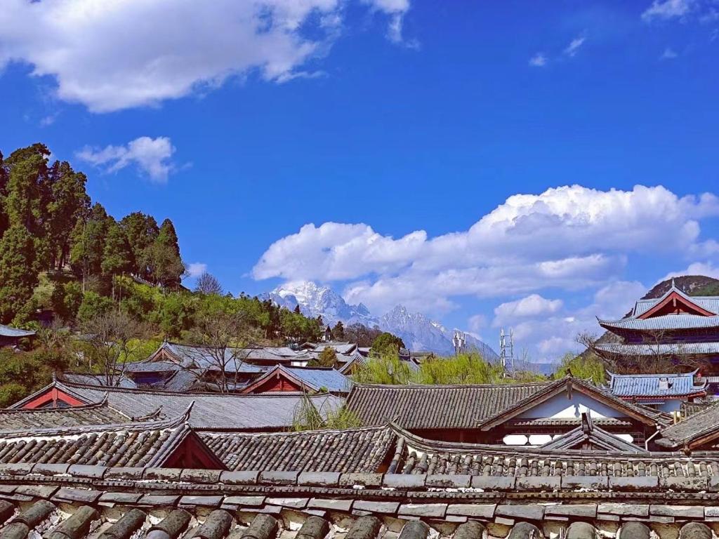 a group of roofs of buildings with mountains in the background at Old Town of Lijiang Meiliju Inn in Lijiang