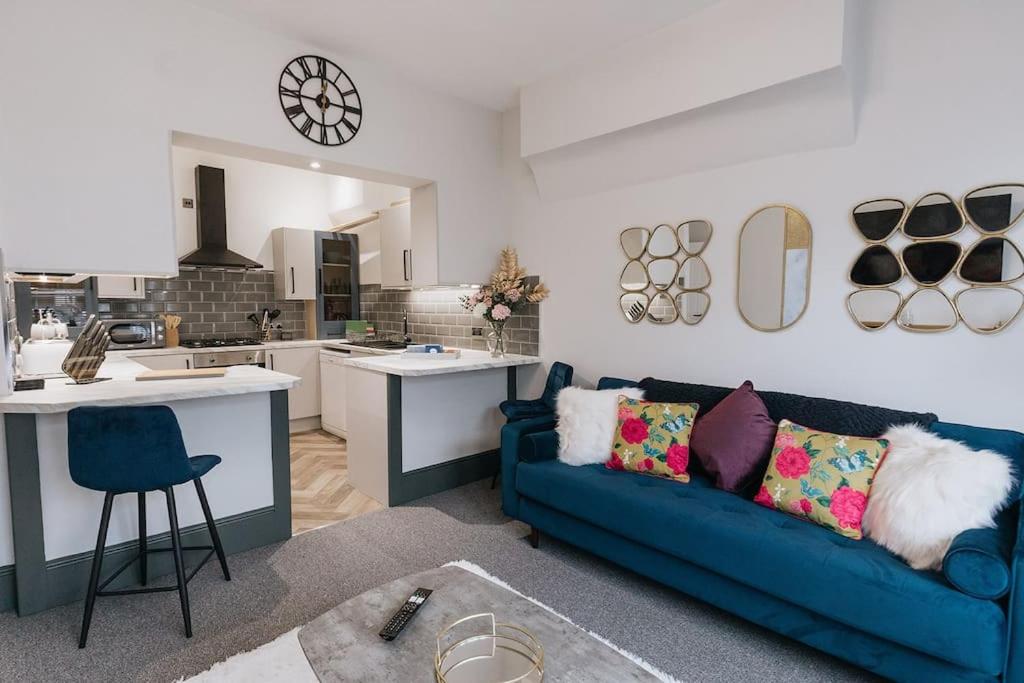 a living room with a blue couch and a kitchen at GROVE HOUSE NO.07 - Luxury Apartment close to the Llandudno Beach in Llandudno