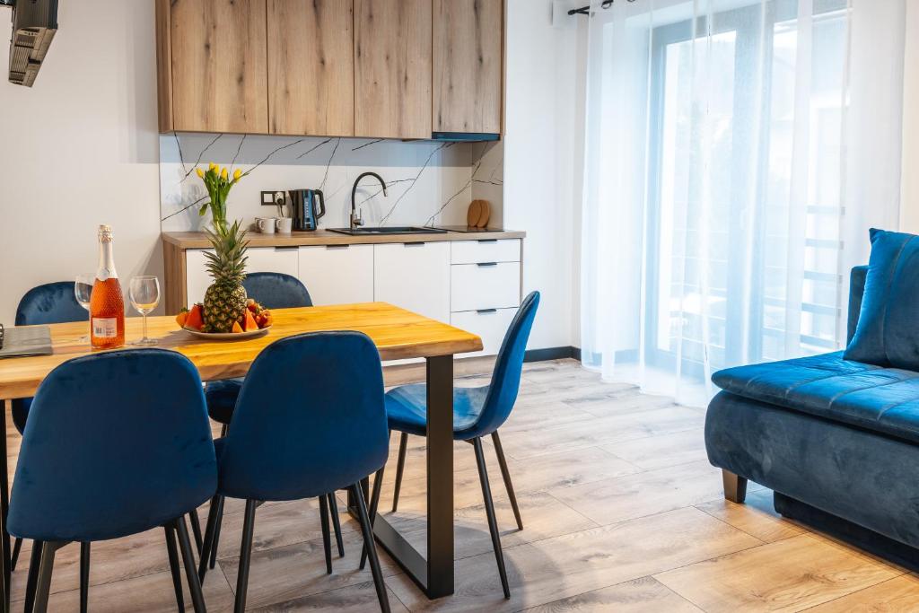 a kitchen and dining room with a wooden table and blue chairs at Apartamenty Pod Wyciągiem in Wisła