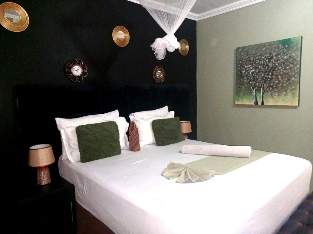 una camera da letto con un grande letto bianco con cuscini verdi di The New Mall Guesthouse a Maun