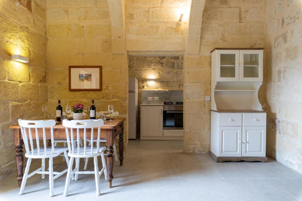 a kitchen with a wooden table and white chairs at Razzett Ghasri in Għasri