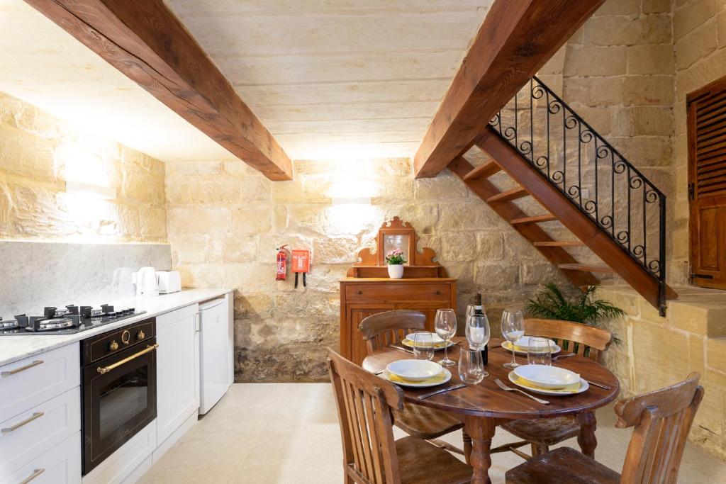 a kitchen with a wooden table and a wooden staircase at Razzett Ghasri in Għasri
