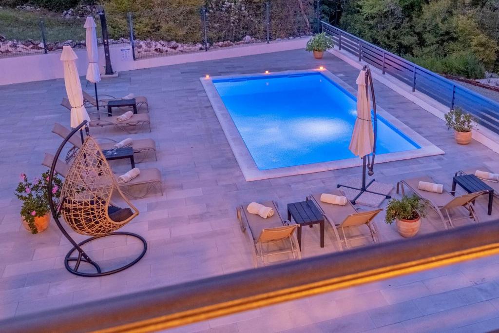 een bovenaanzicht van een zwembad met stoelen en parasols bij Villa ARIA VALLIS in Tribalj