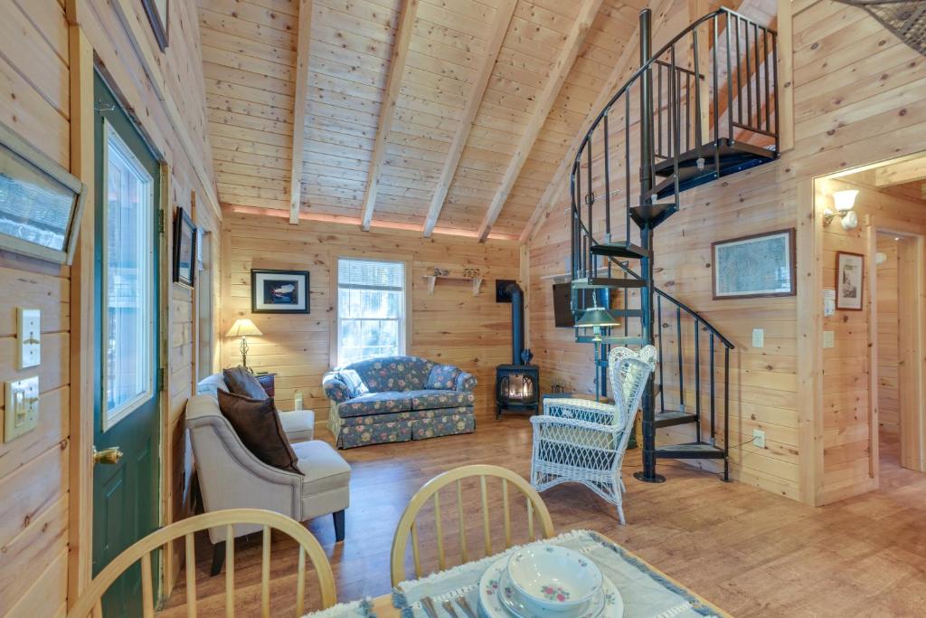 a living room with a spiral staircase in a log cabin at Maine Lodging Near Acadia National Park! in Bernard