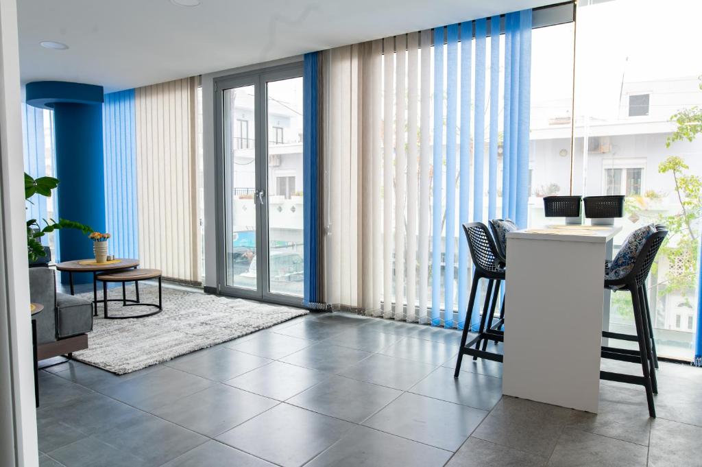 a living room with a counter and chairs and windows at Zoes Apartment Kos Town in Kos