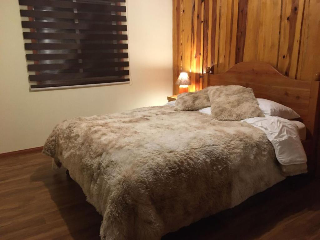 - une chambre avec un grand lit et une tête de lit en bois dans l'établissement Ruka Pucón Hostel, à Pucón