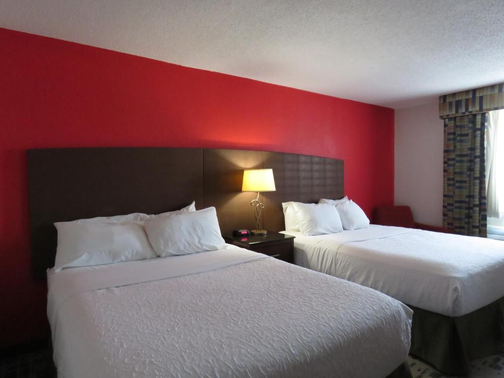 American Inn & Suites في Ferndale: غرفة فندقية بسريرين وجدار احمر