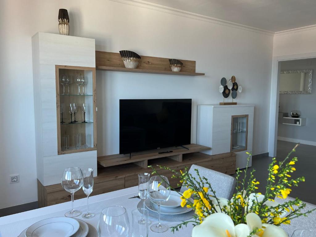 Apartamentos Maria de Lucia- Ático في Arou: غرفة معيشة مع طاولة مع نظارة وتلفزيون