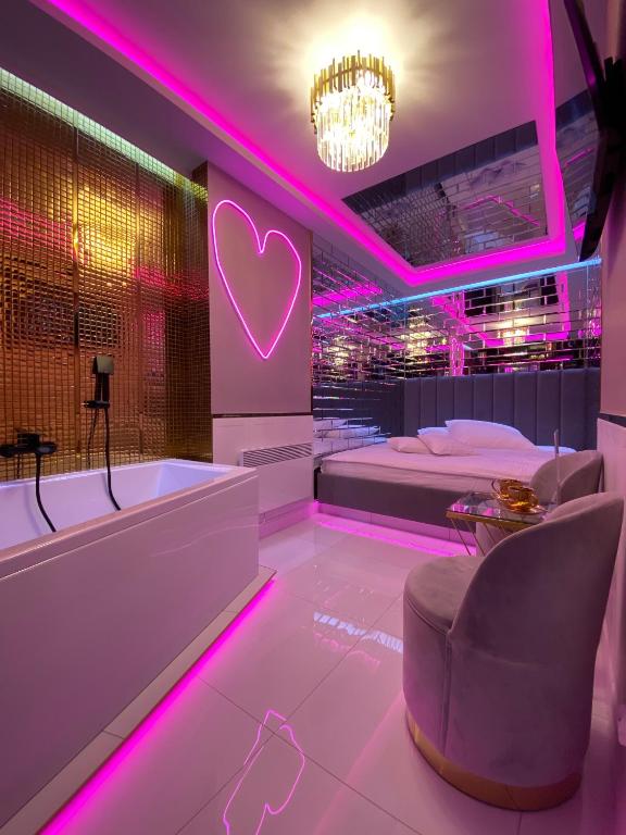 un bagno con vasca e un letto con illuminazione rosa di Apartament "Love Paradise" Centrum z dużą wanną dla Dwojga a Gniezno