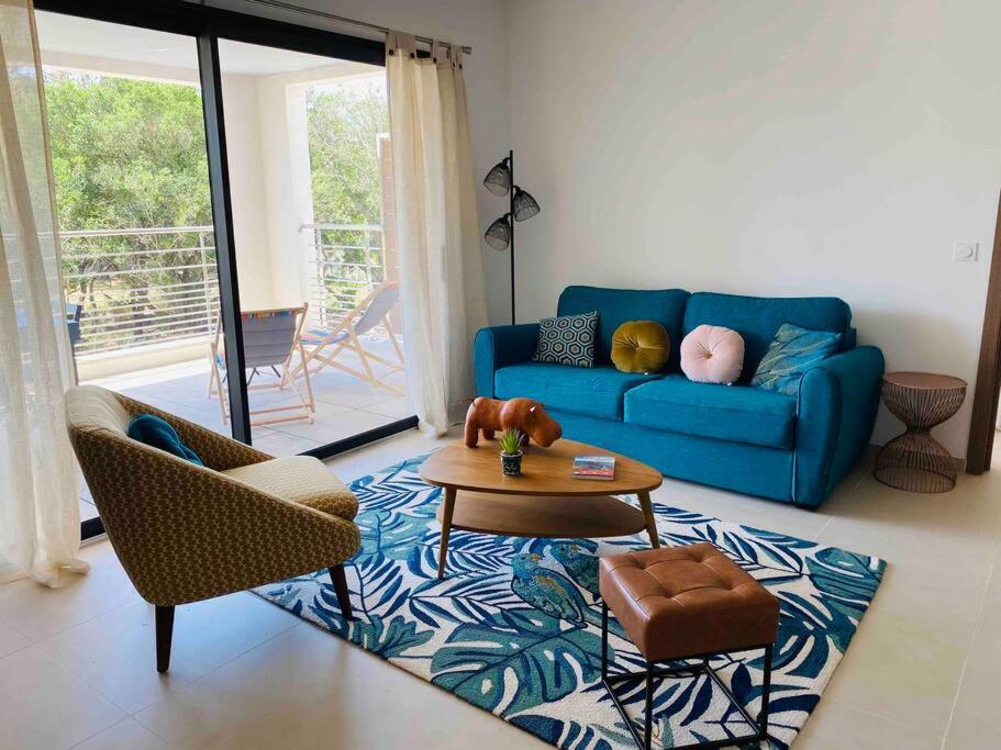 un salon avec un canapé bleu et une table dans l'établissement T2 neuf 4 personnes avec piscine/terrain tennis, à Porto-Vecchio
