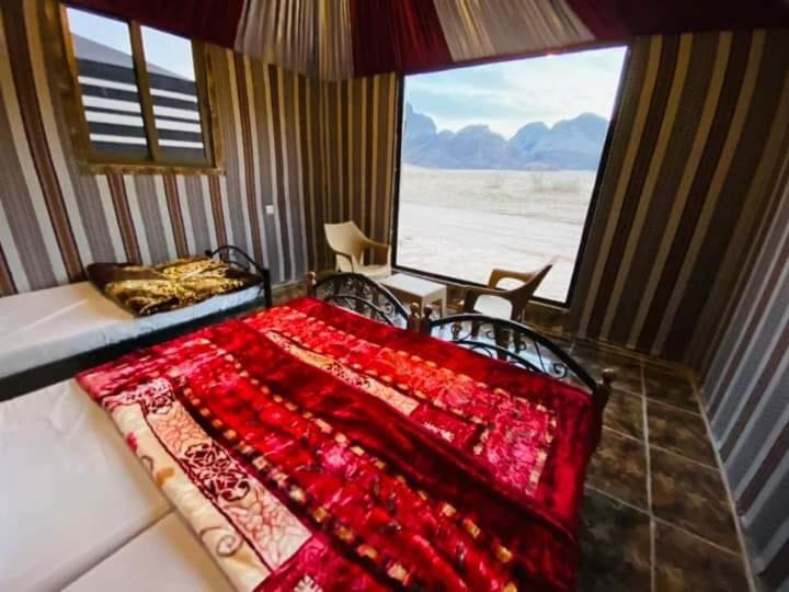 a bedroom with a bed and a large window at Desert guide camp in Wadi Rum