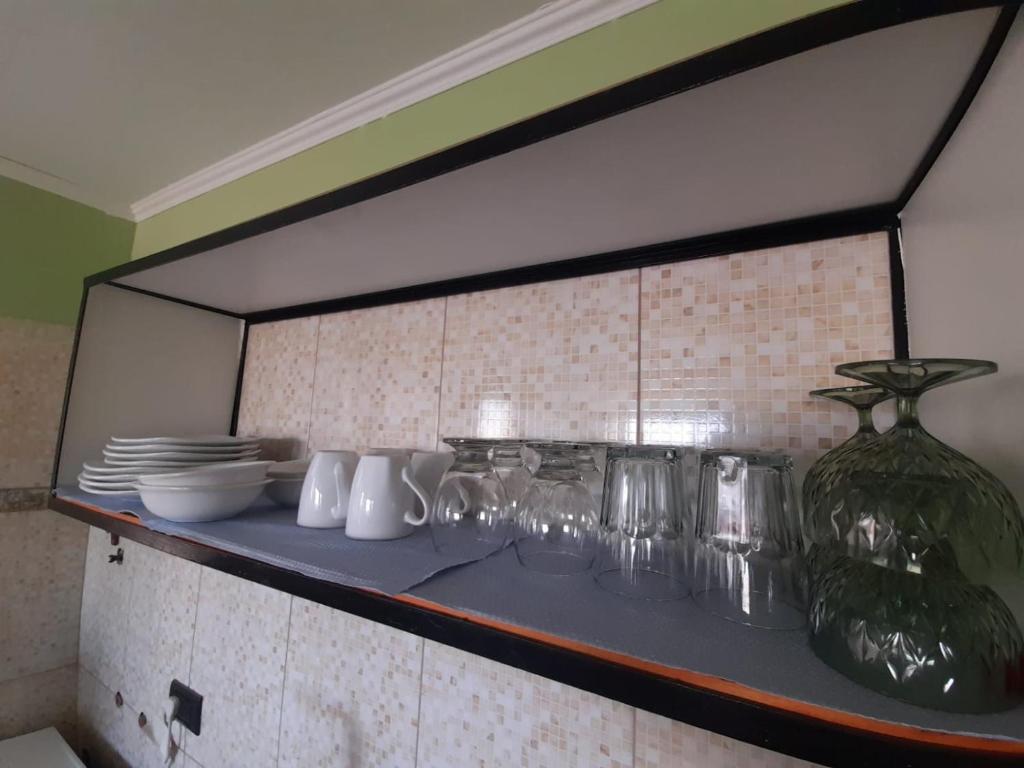 un estante con vasos y platos y un jarrón en Apartamentos km4, en Comodoro Rivadavia