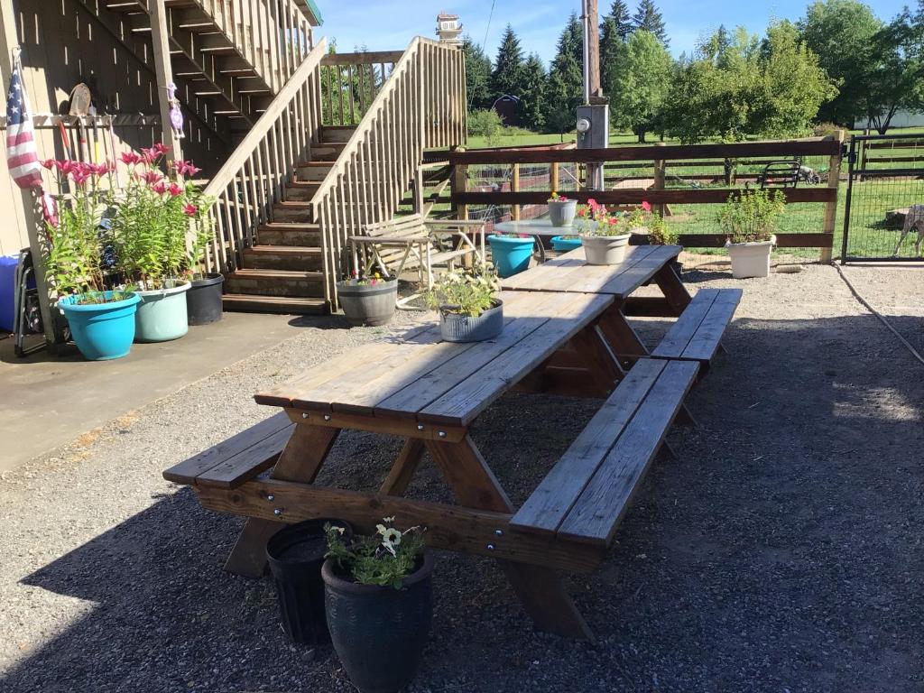 een groep houten picknicktafels met potplanten bij 3G Farms Studio 