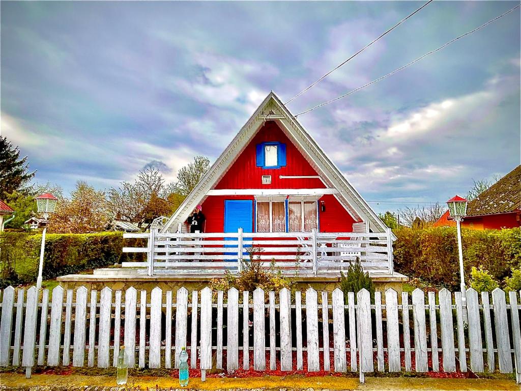 a red and blue house behind a white fence at Aqua Faház in Mesteri