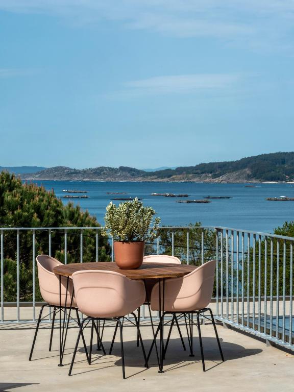 a table with chairs and a potted plant on a balcony at INSUA BEACH HOUSE in Pontevedra