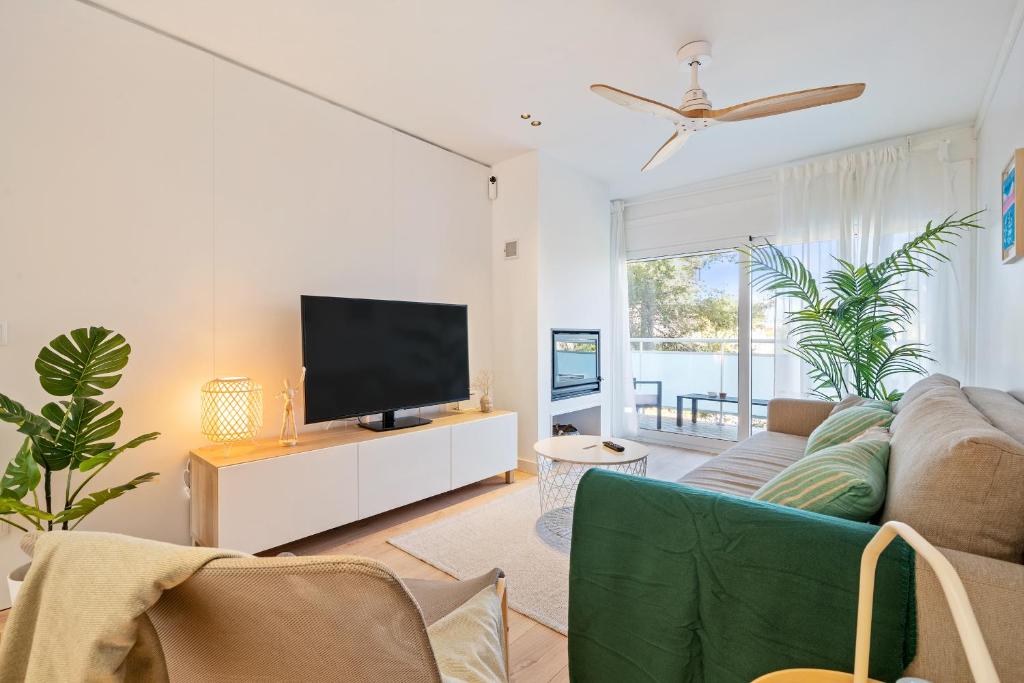 sala de estar con TV y sofá en Hauzify I Apartament Westland, en Salou