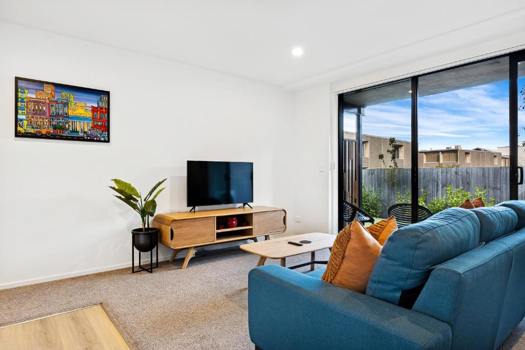 een woonkamer met een blauwe bank en een tv bij 1 Bedroom City Base with Free Car Park in Christchurch
