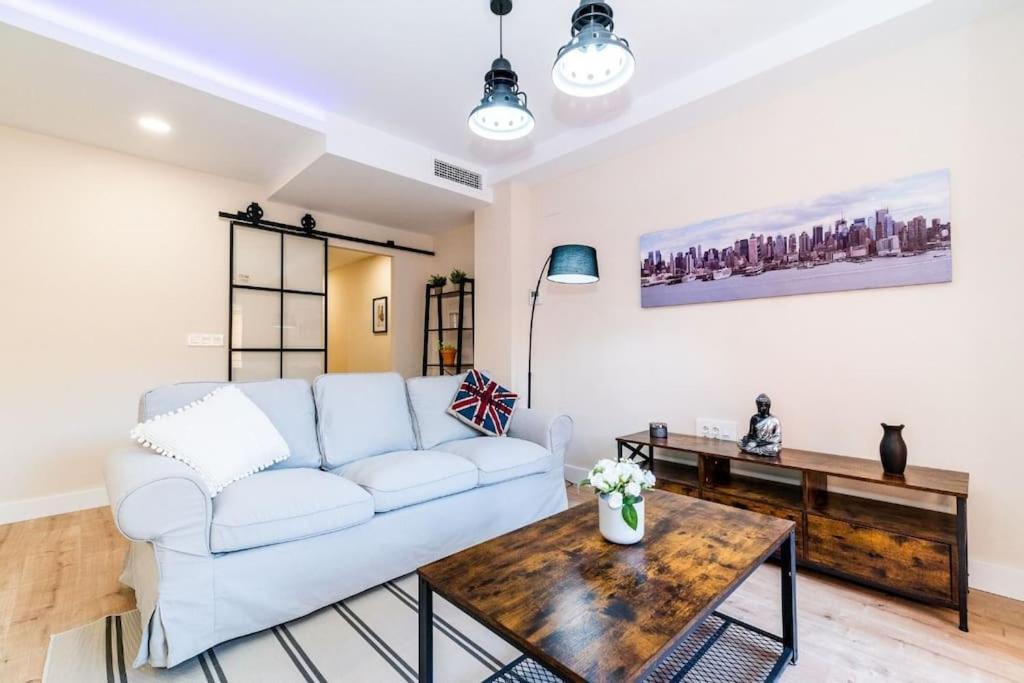 Modern Apartment close to the city center and Alhambra في غرناطة: غرفة معيشة مع أريكة بيضاء وطاولة