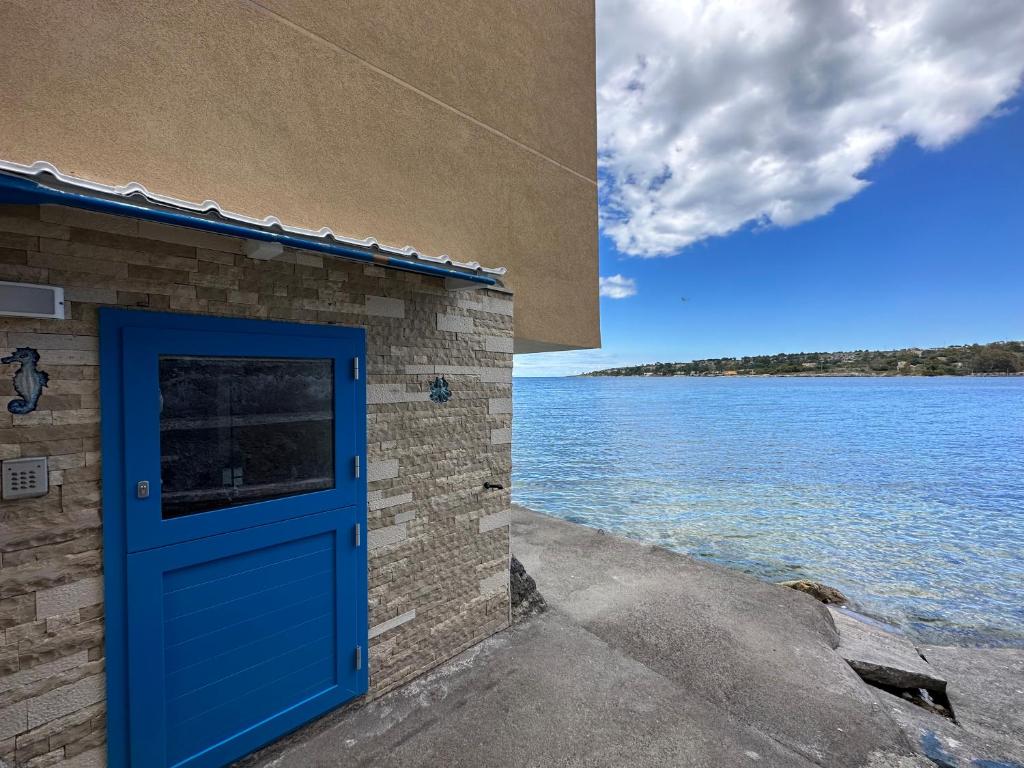 a blue door on a building next to a body of water at La Casetta sul mare in Brucoli