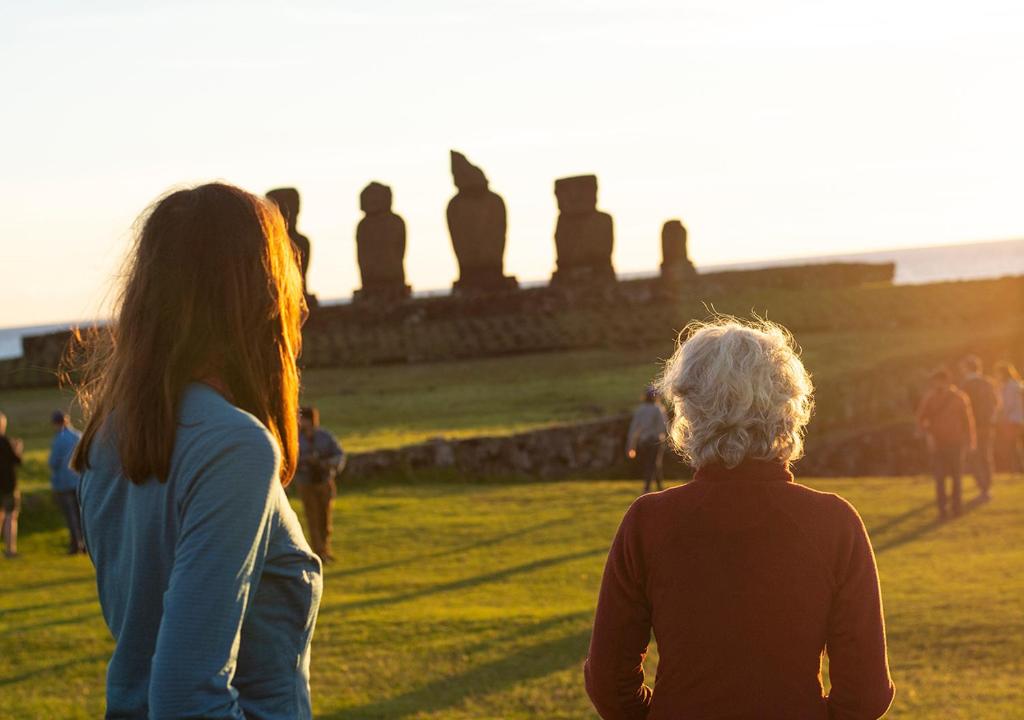 two women standing in a field looking at a group of people at Explora en Rapa Nui - All Inclusive in Hanga Roa