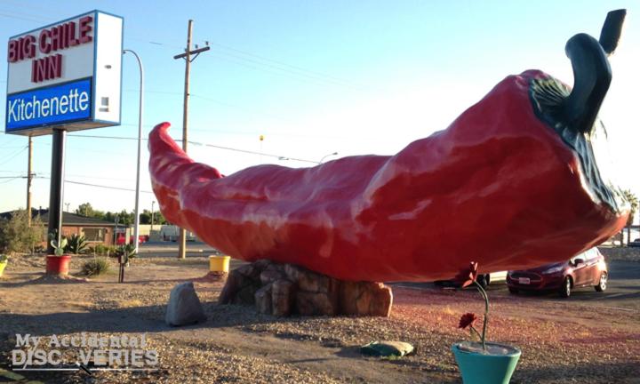 uma grande estátua de peixe vermelho em frente a um posto de gasolina em Big Chile Inn & Suites em Las Cruces