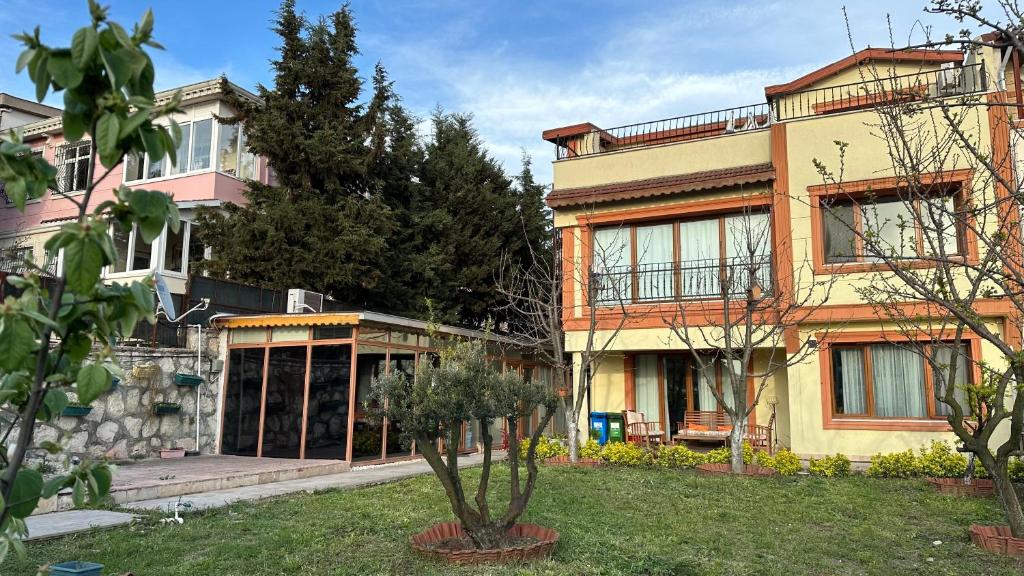 a house with a tree in the front yard at Doğa Villa Guest House in Büyükçekmece