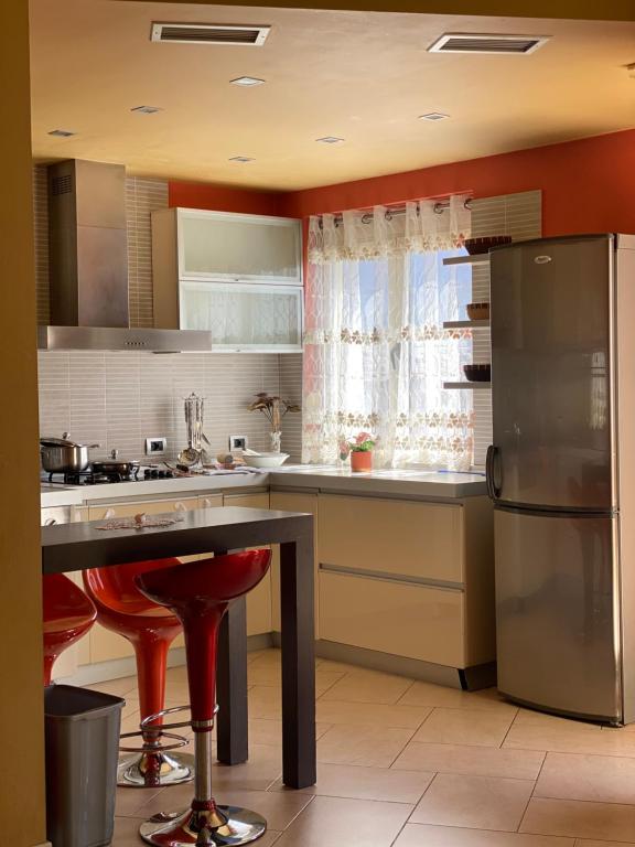 a kitchen with a refrigerator and a table with red stools at Sunshine Place in Elbasan