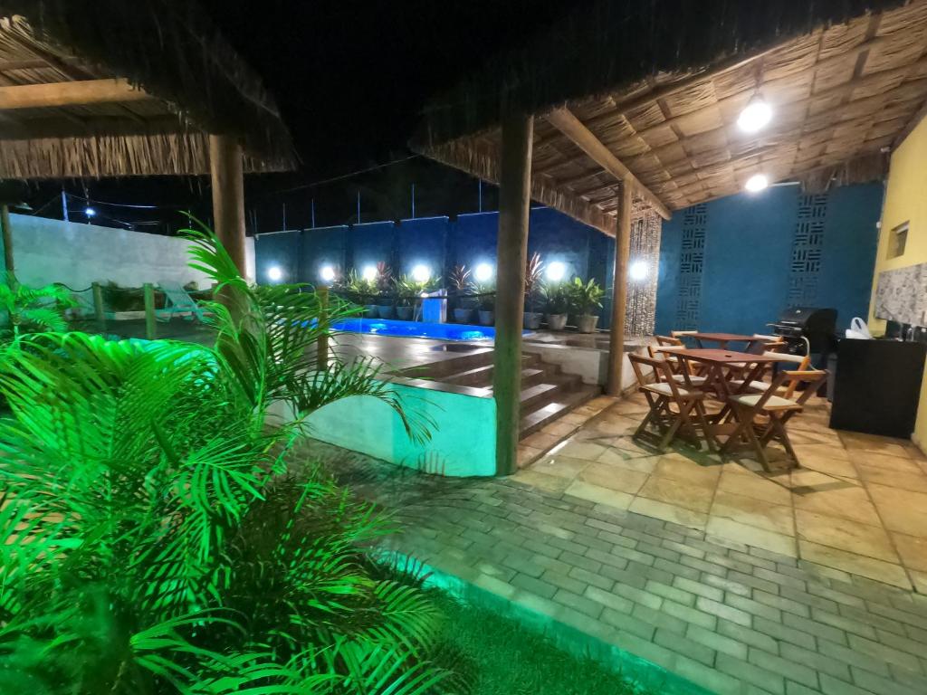 Un patio con mesa y sillas y una piscina. en Wind Village Chalés, en São Miguel do Gostoso