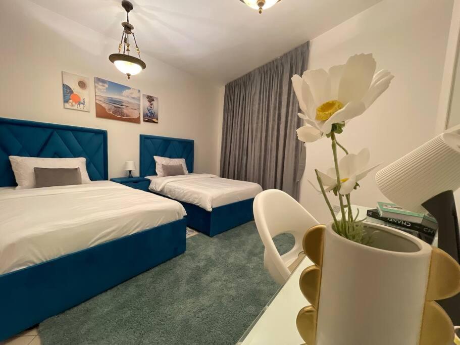 a hotel room with two beds and a vase with a flower at Waterfront Royal 3BR apartment in Sharjah