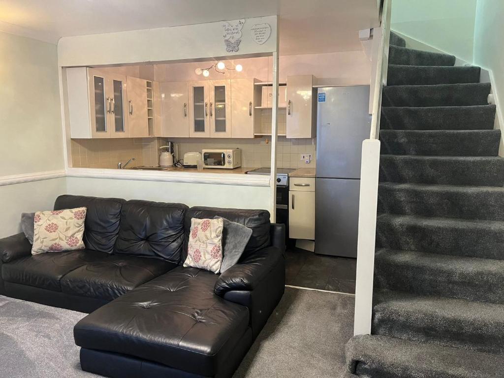 een woonkamer met een bank en een trap bij LONDON 1 BED COSY HOUSE in Norwood