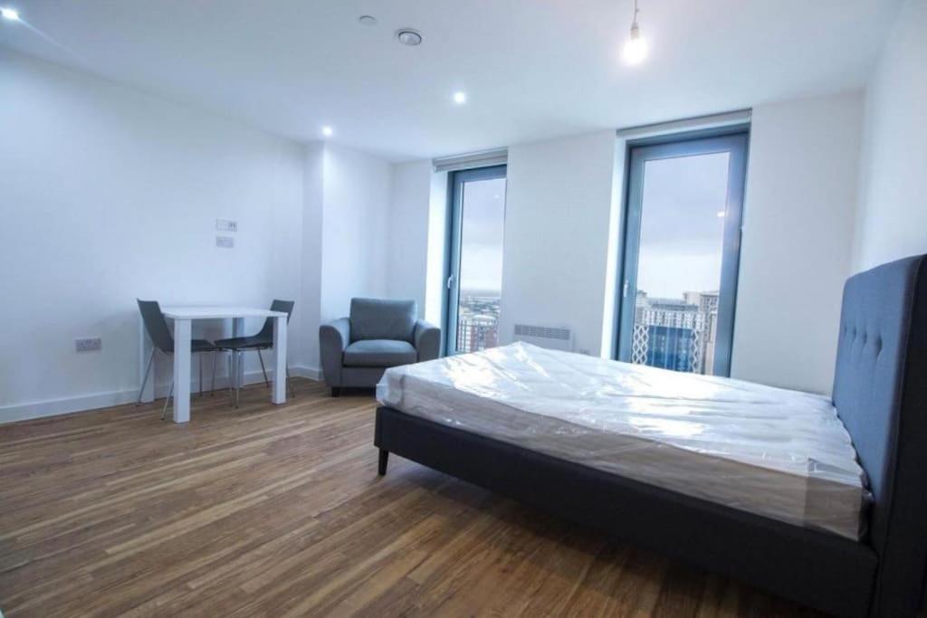 1 dormitorio con cama, mesa y ventanas en Luxury Apartment near Media City, en Mánchester