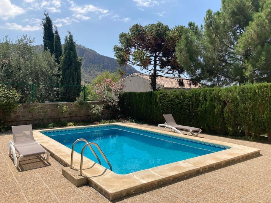 una piscina con 2 sillas y una piscina en Casa Surya - unique country house near Granada en Nigüelas