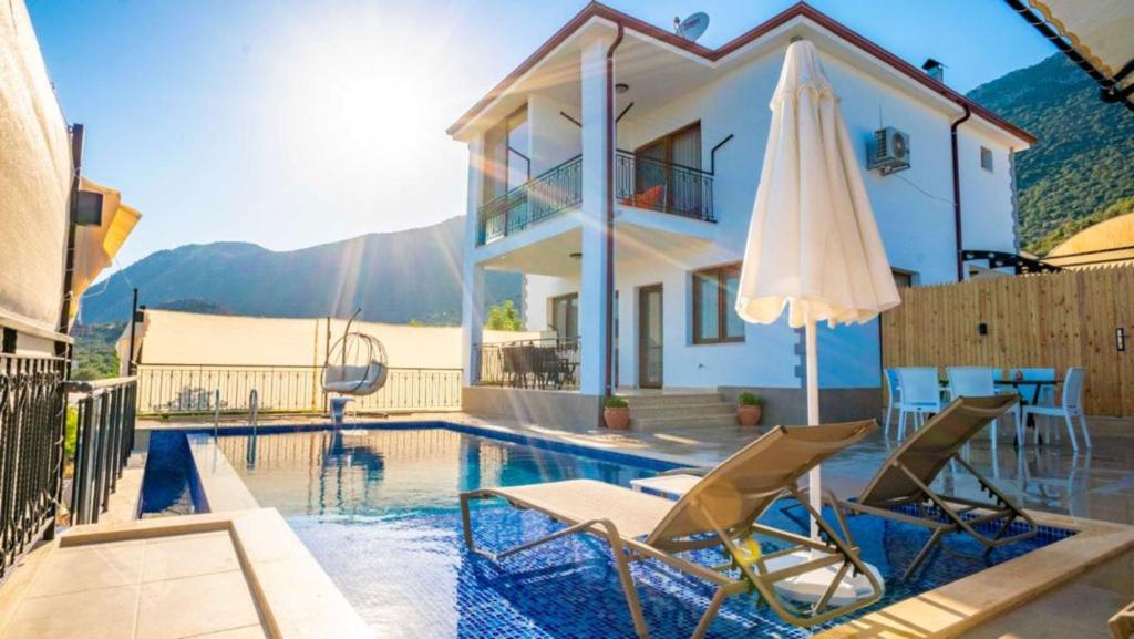 Villa mit einem Pool, 2 Stühlen und einem Sonnenschirm in der Unterkunft VİLLA TANYERİ in Kaş