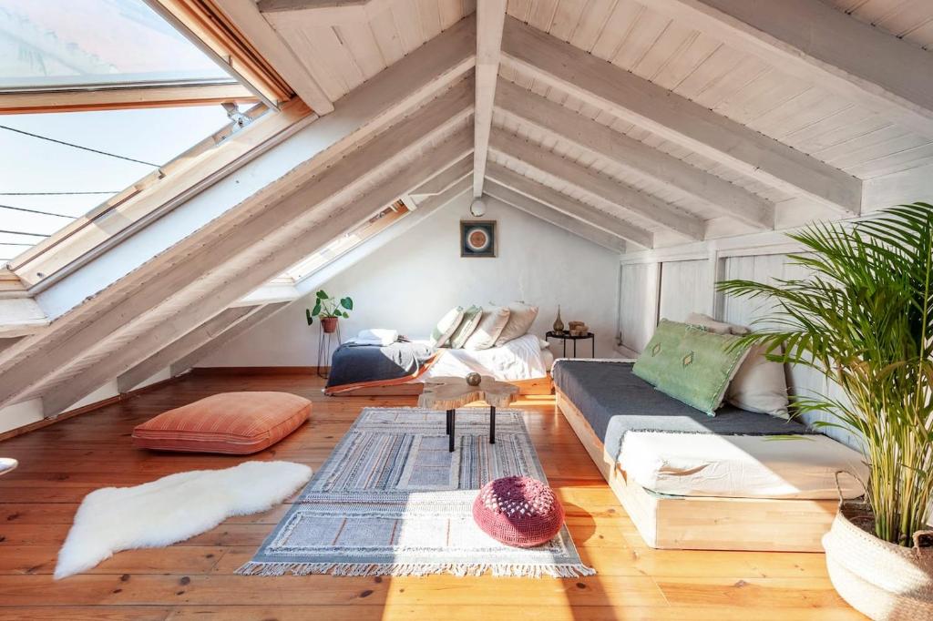 a attic living room with a couch and some plants at Oliveira Surf House Ericeira in Santo Isidoro