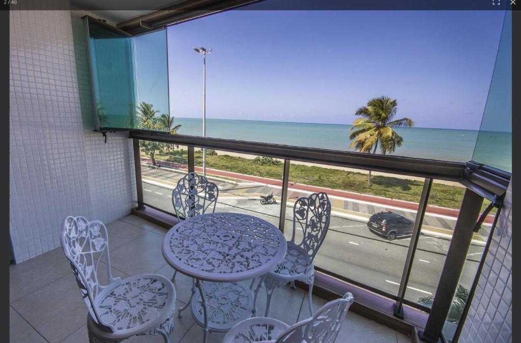 a balcony with a table and chairs and the ocean at Luxor Paulo Miranda Frente ao mar in João Pessoa
