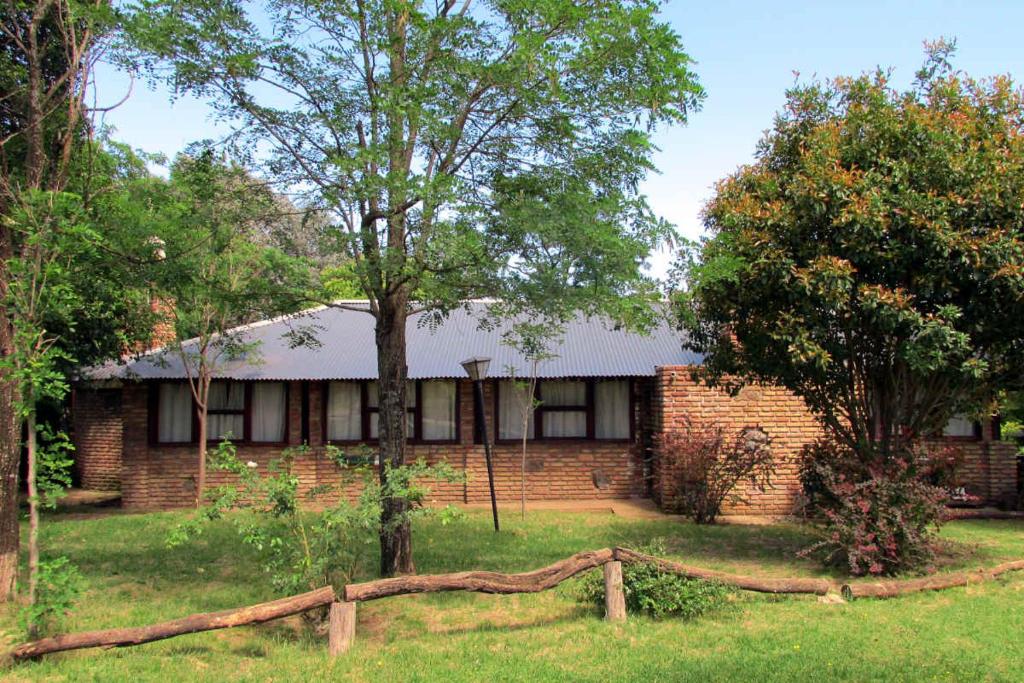 ein Backsteinhaus mit einem Zaun im Hof in der Unterkunft LUNA CAUTIVA in Santa Rosa de Calamuchita