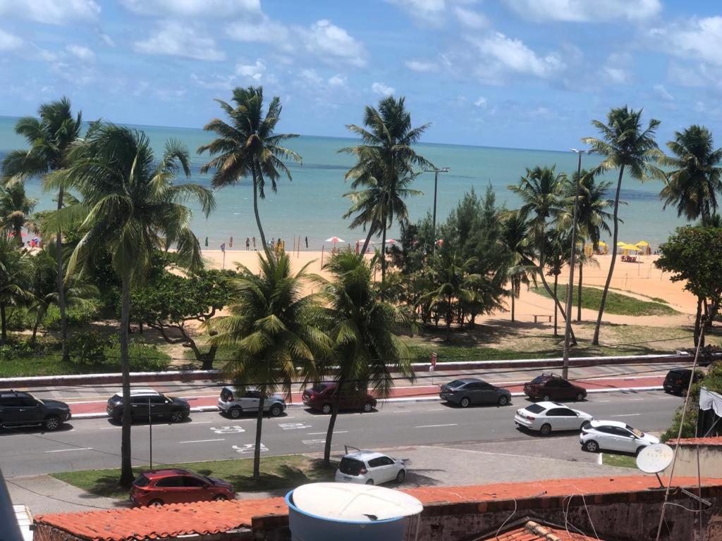 uma vista para uma praia com palmeiras e carros em MAR DO CABO BRANCO YELLOW residence em João Pessoa