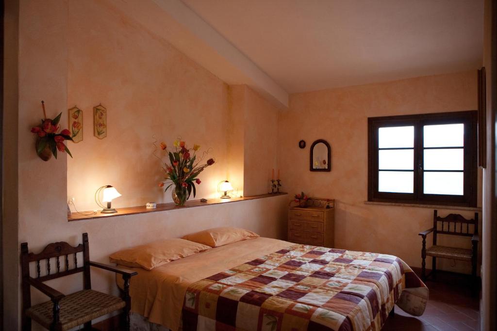 サンタ・フィオーラにあるAgriturismo La Leggendaのベッドルーム1室(ベッド1台、椅子2脚、窓付)