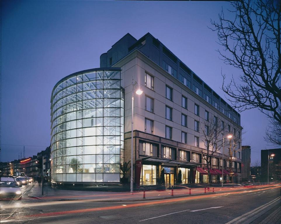 un gran edificio de cristal en una calle de la ciudad por la noche en The Green en Dublín