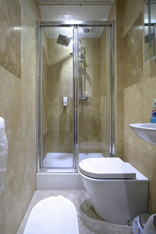 a bathroom with a shower and a toilet and a sink at Beaconsfield Hotel in London