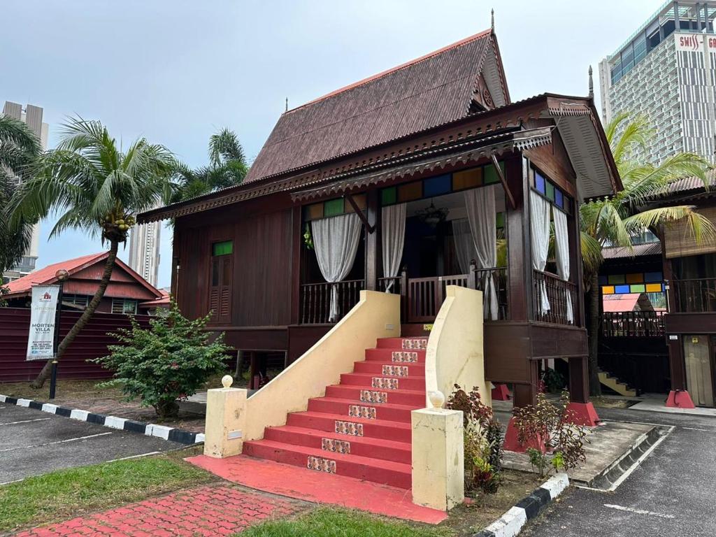 a small house with a red staircase in a parking lot at MORTEN VILLA MELAKA in Melaka