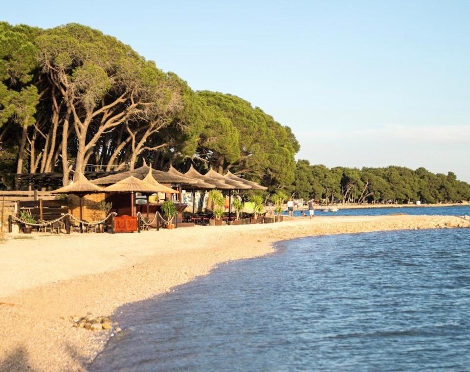 a beach with tables and umbrellas and the water at Apartment David in Biograd na Moru