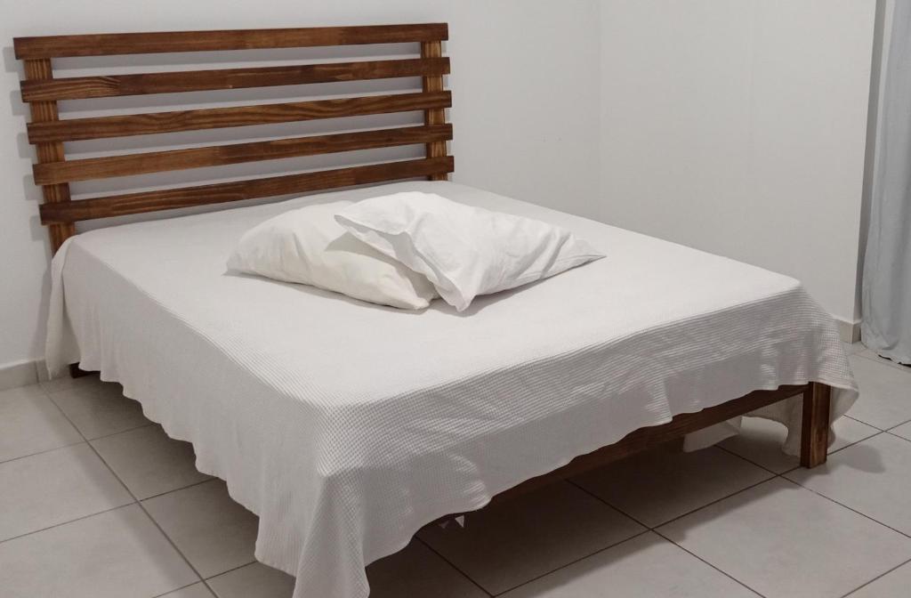 a bed with white sheets and a pillow on it at Apartamento aconchegante in Ribeirão Preto